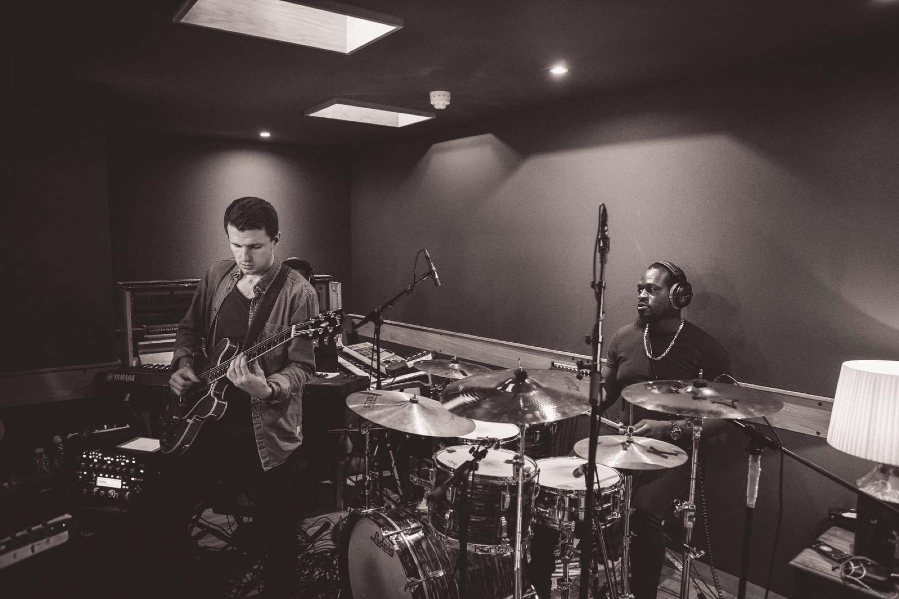 David Niskin recording electric guitar with a drummer in a professional studio.